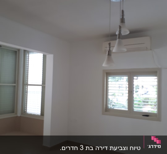 חדר ריק עם קירות לבנים ותאורה תלויה